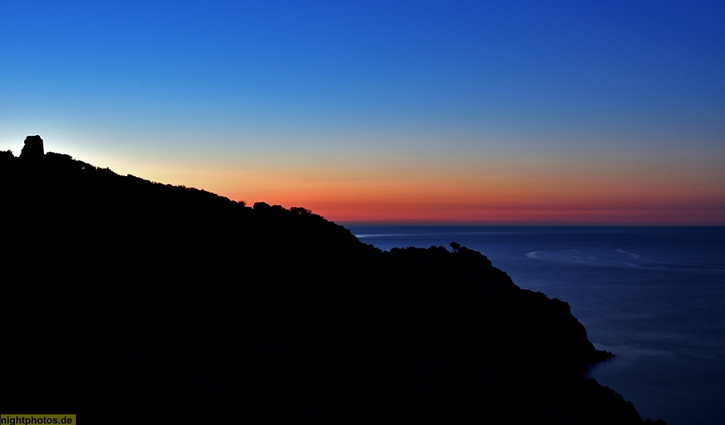 Mallorca Cala Ratjada Sonnenuntergang am Leuchtturm mit Blick auf Wachturmruine Torre Esbucada aus dem 17 Jhdt