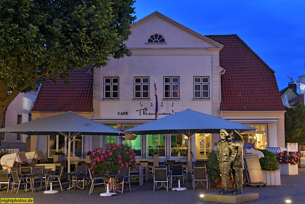 Neustadt in Holstein. Cafe Thienemanns. Putzbau in Ecklage erbaut 1817 mit Krüppelwalmdach und Quergiebel. Kremper Strasse 1. Davor Fischerdenkmal von Serge Mangin 1994